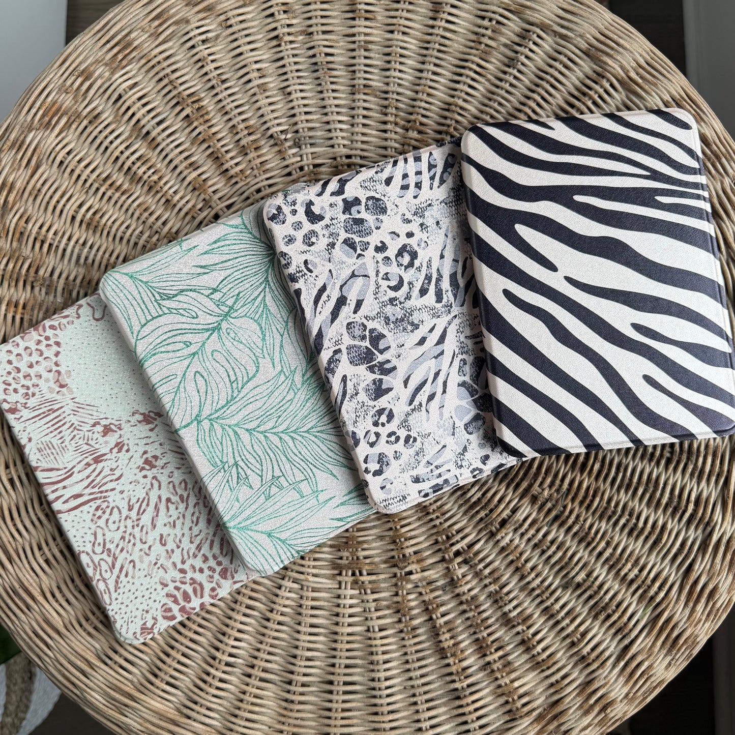 Four patterned kindle cases on a wicker surface