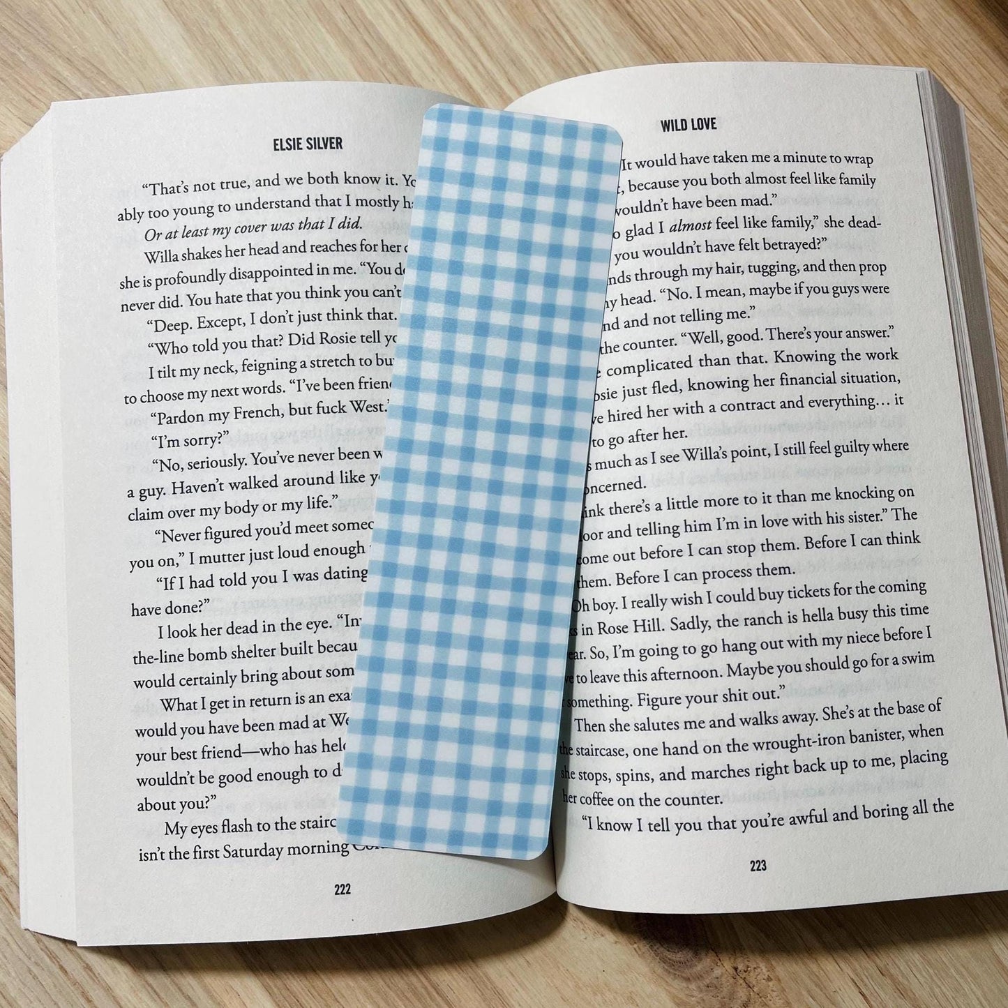 Open book with a blue and white checkered bookmark on a wooden surface