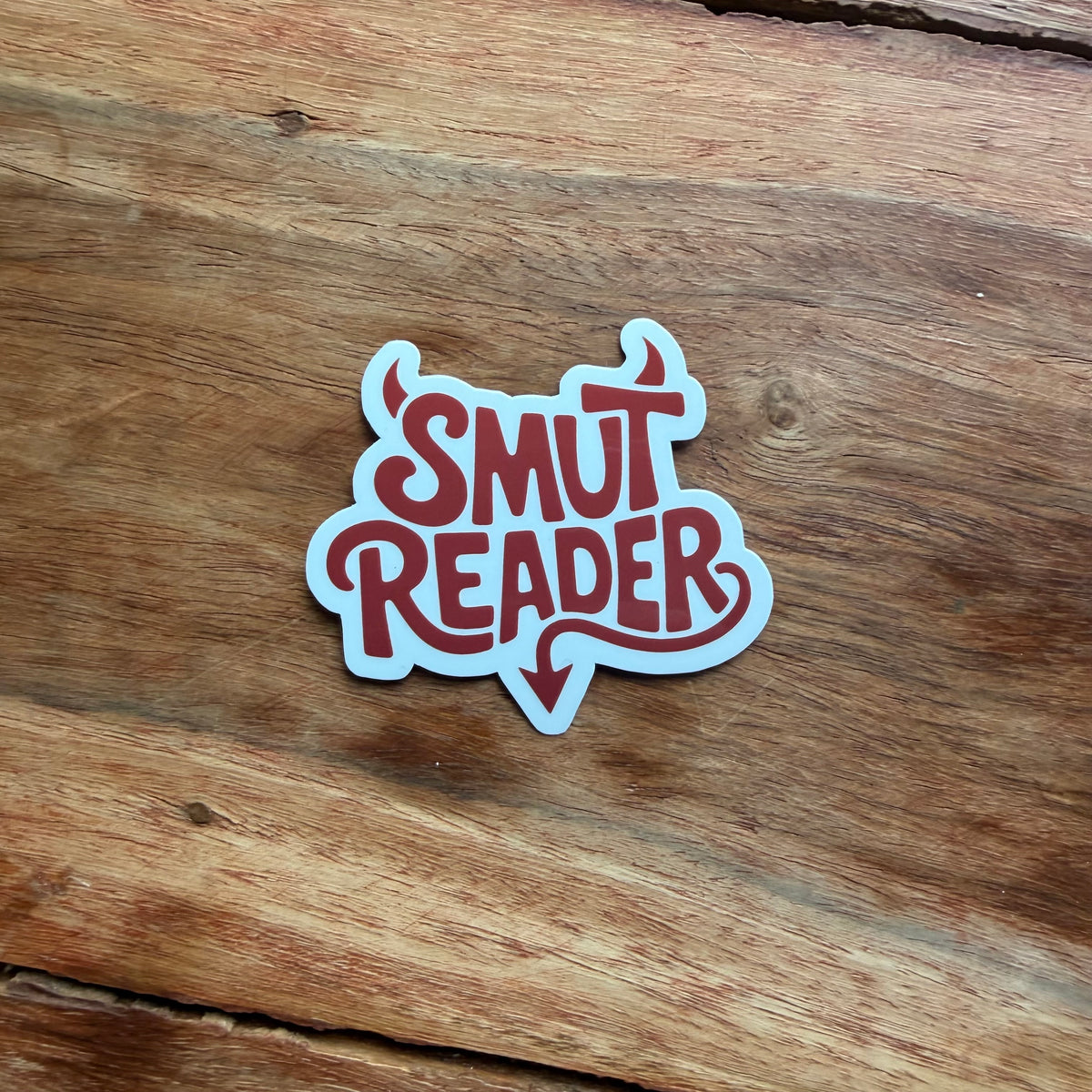 Sticker with 'Smut Reader' text on a wooden surface