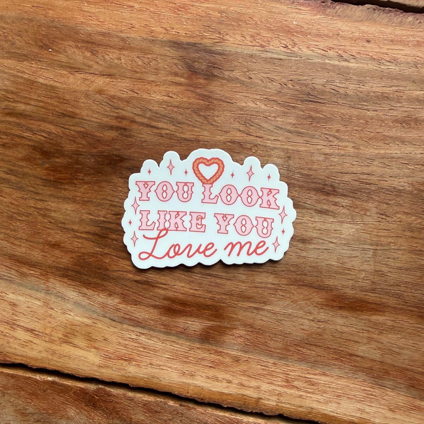 Sticker with 'You Look Like You Love Me' text on a wooden surface