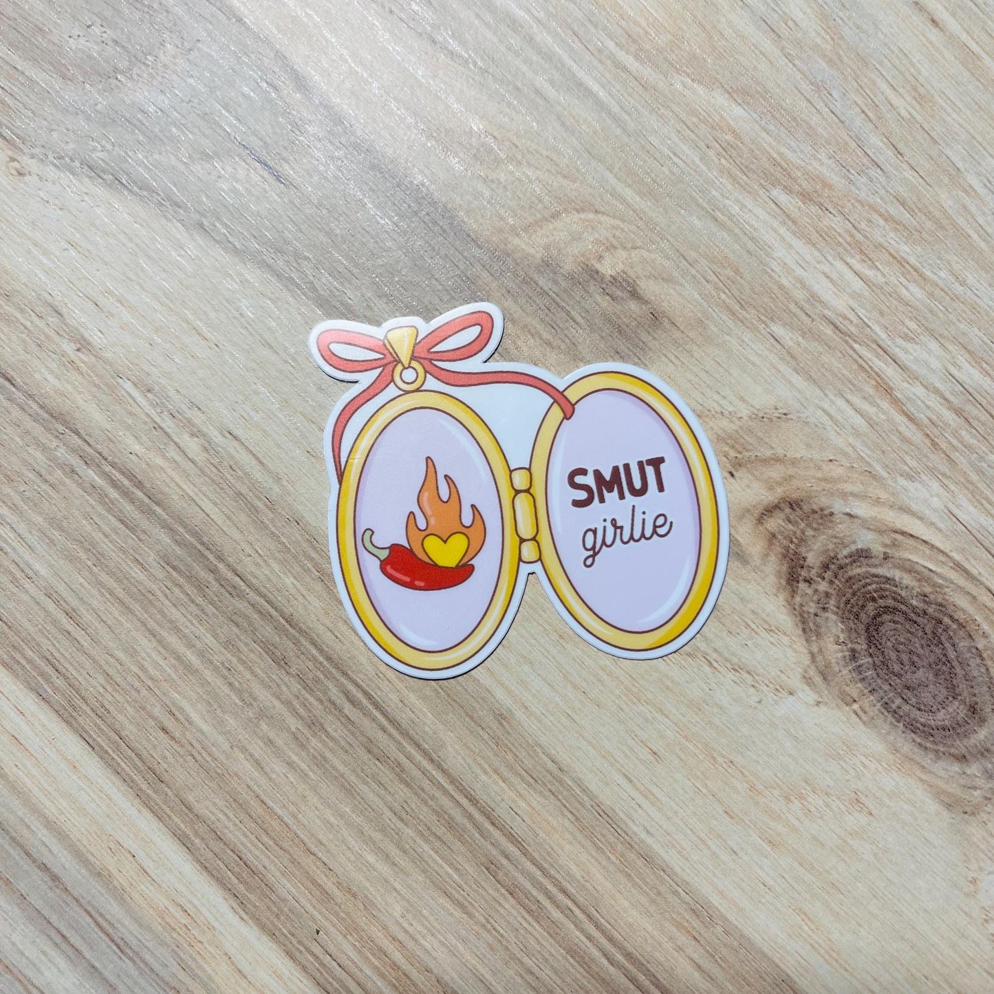 Sticker with 'Smut girlie' text on a wooden surface