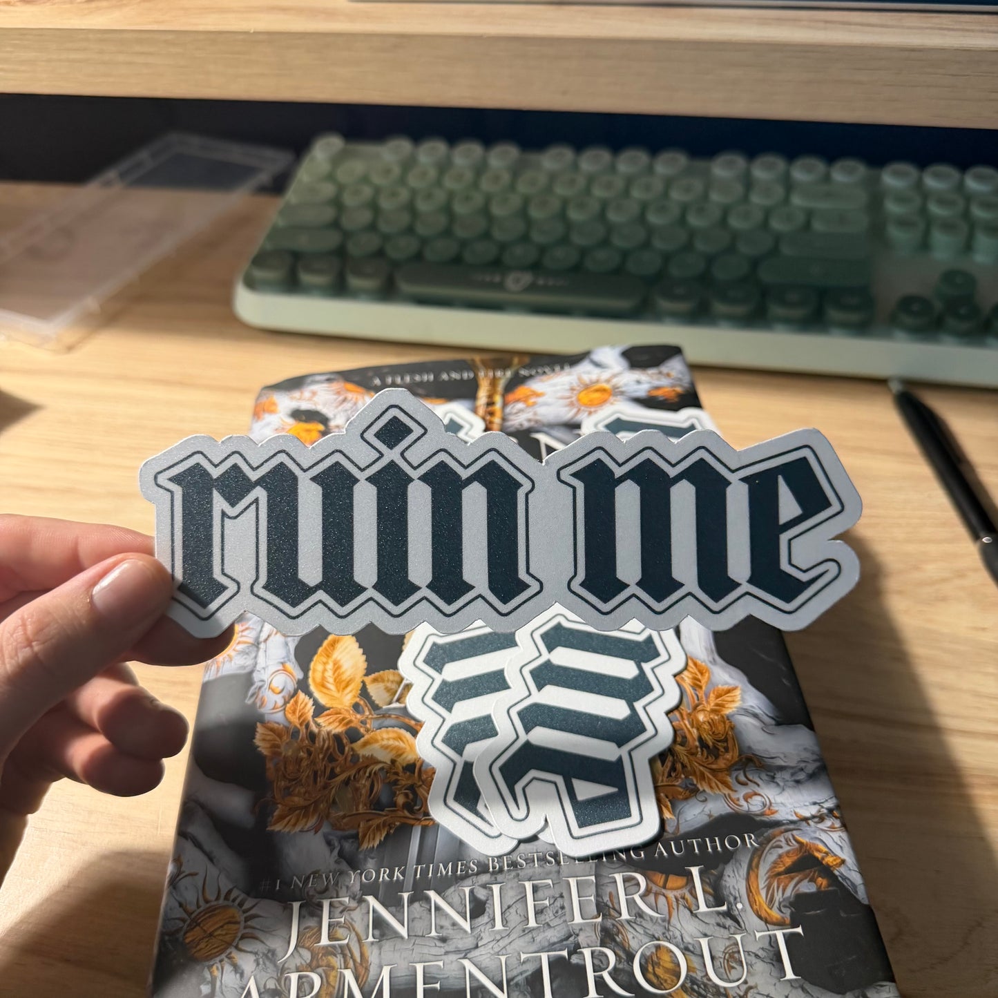 A die cut bookmark with 'Ruin me' text held over a book on a desk