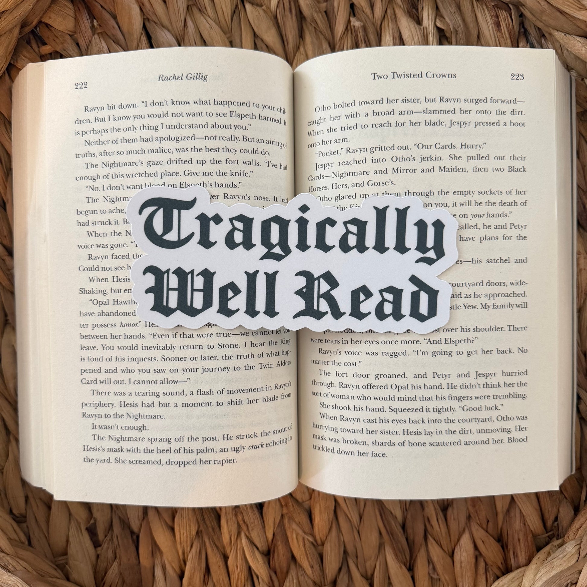 Open book with 'Tragically Well Read' text bookmark overlay on a woven surface