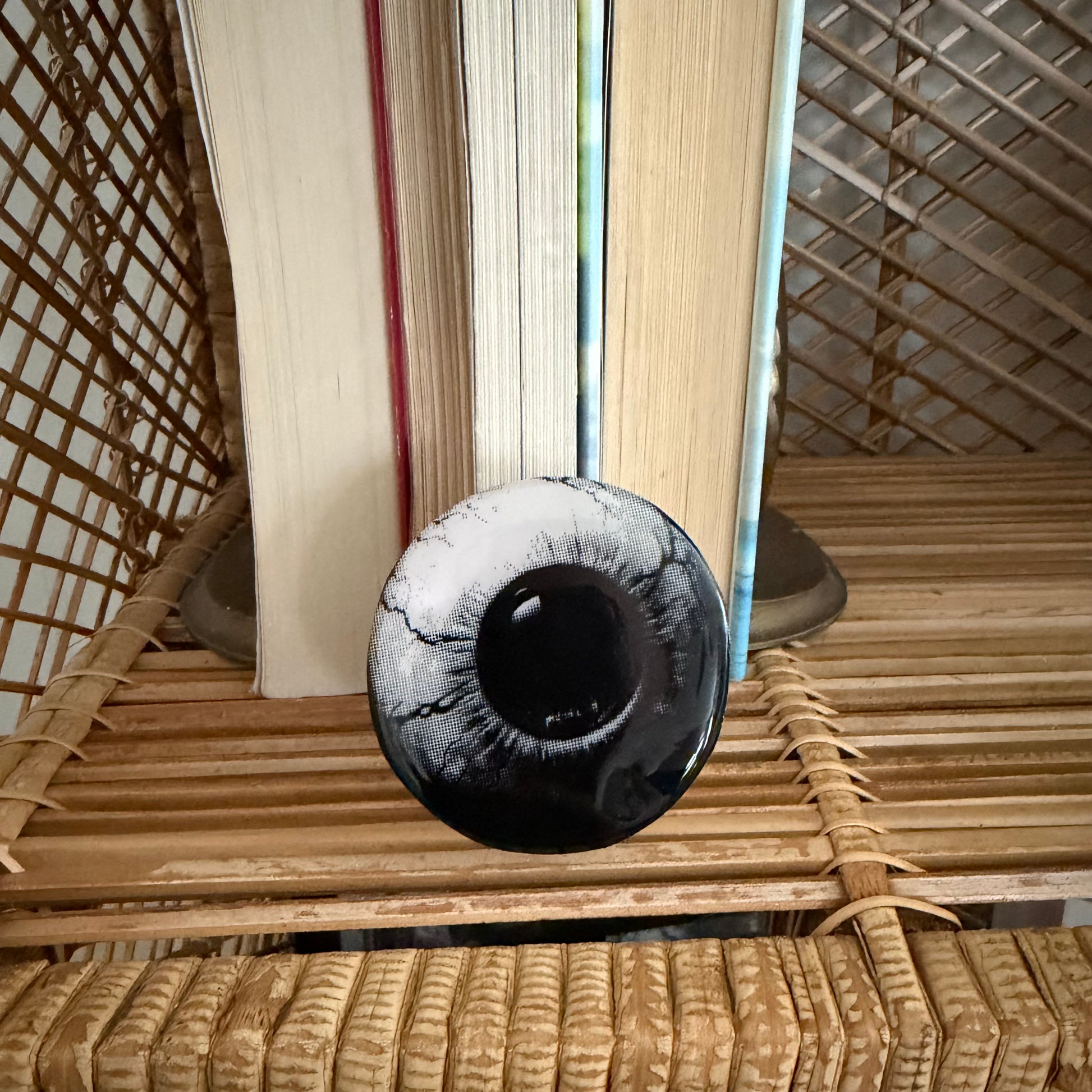 Black and white eye-shaped phone grip on a textured surface