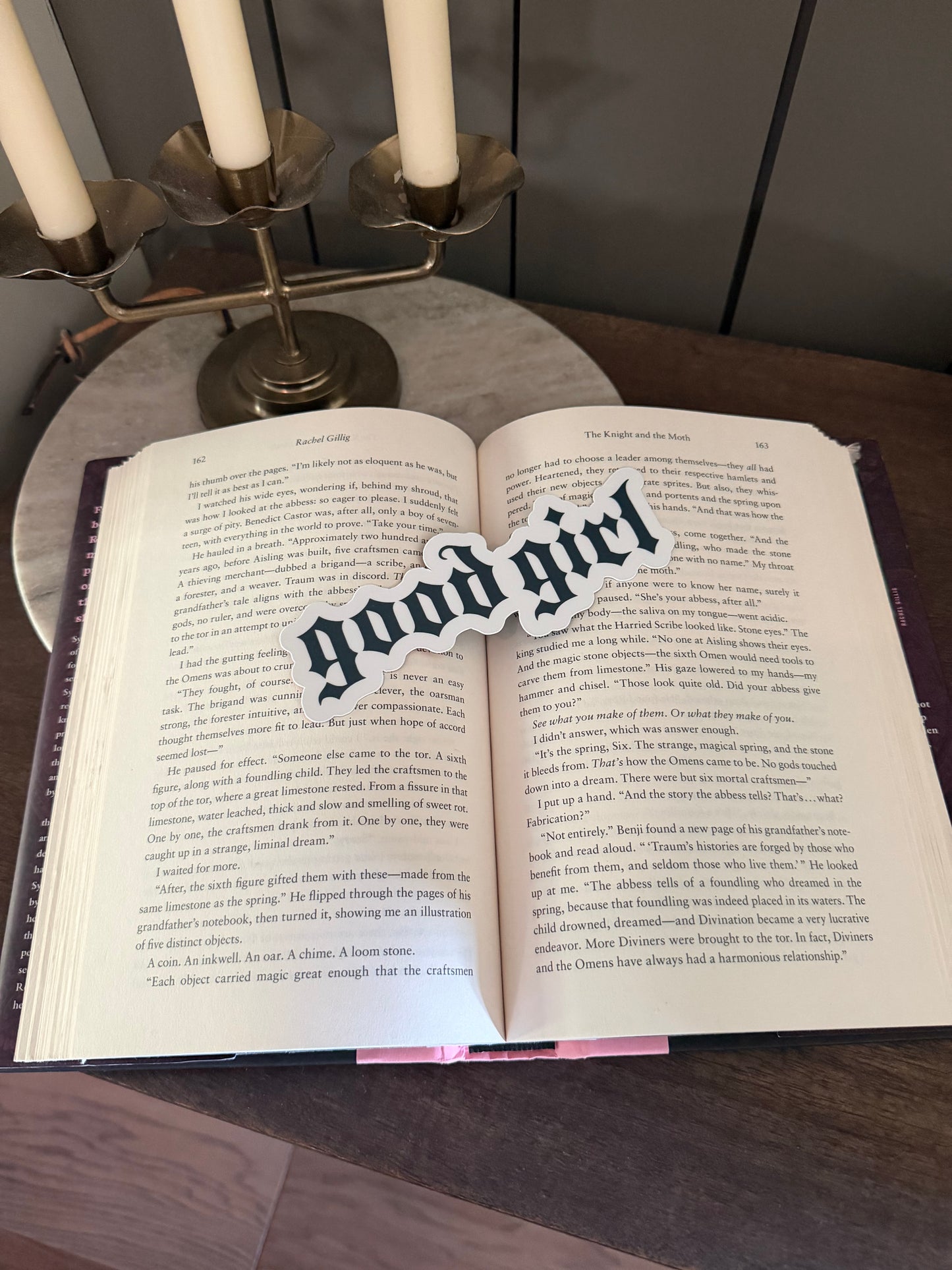 Open book with 'good girl' bookmark on a wooden surface
