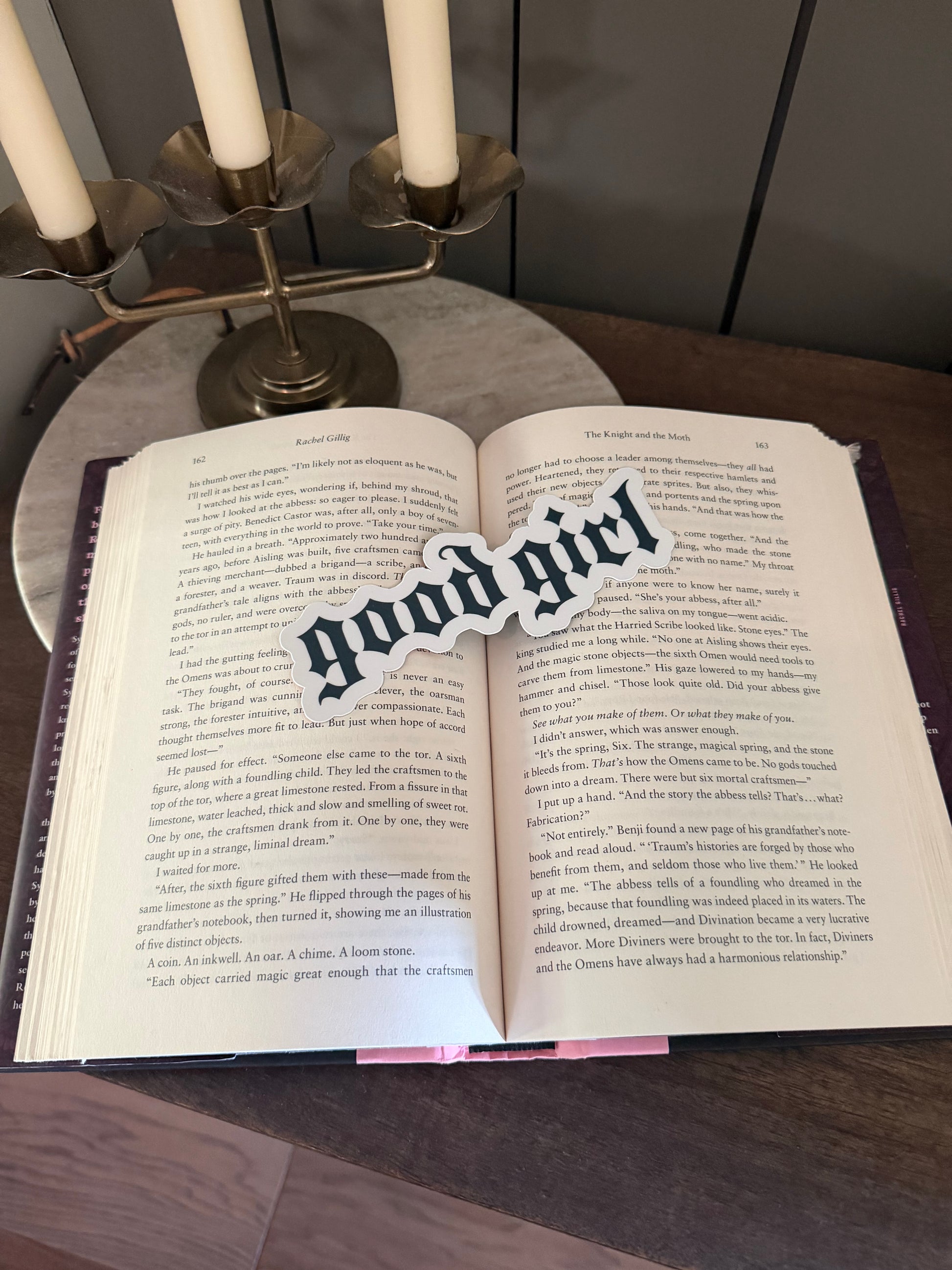 Open book with 'good girl' bookmark on a wooden surface