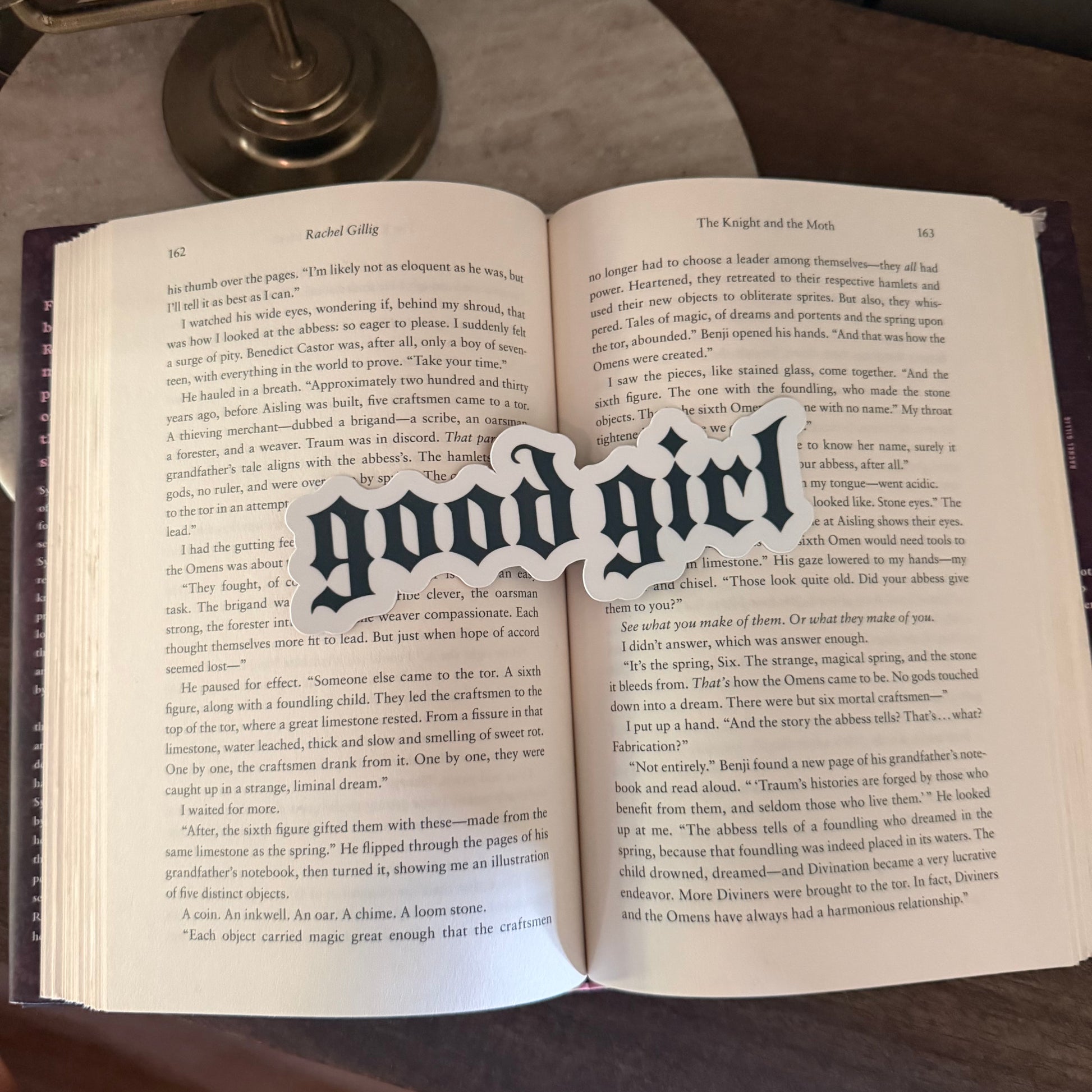 Open book with a 'good girl' bookmark on a wooden surface