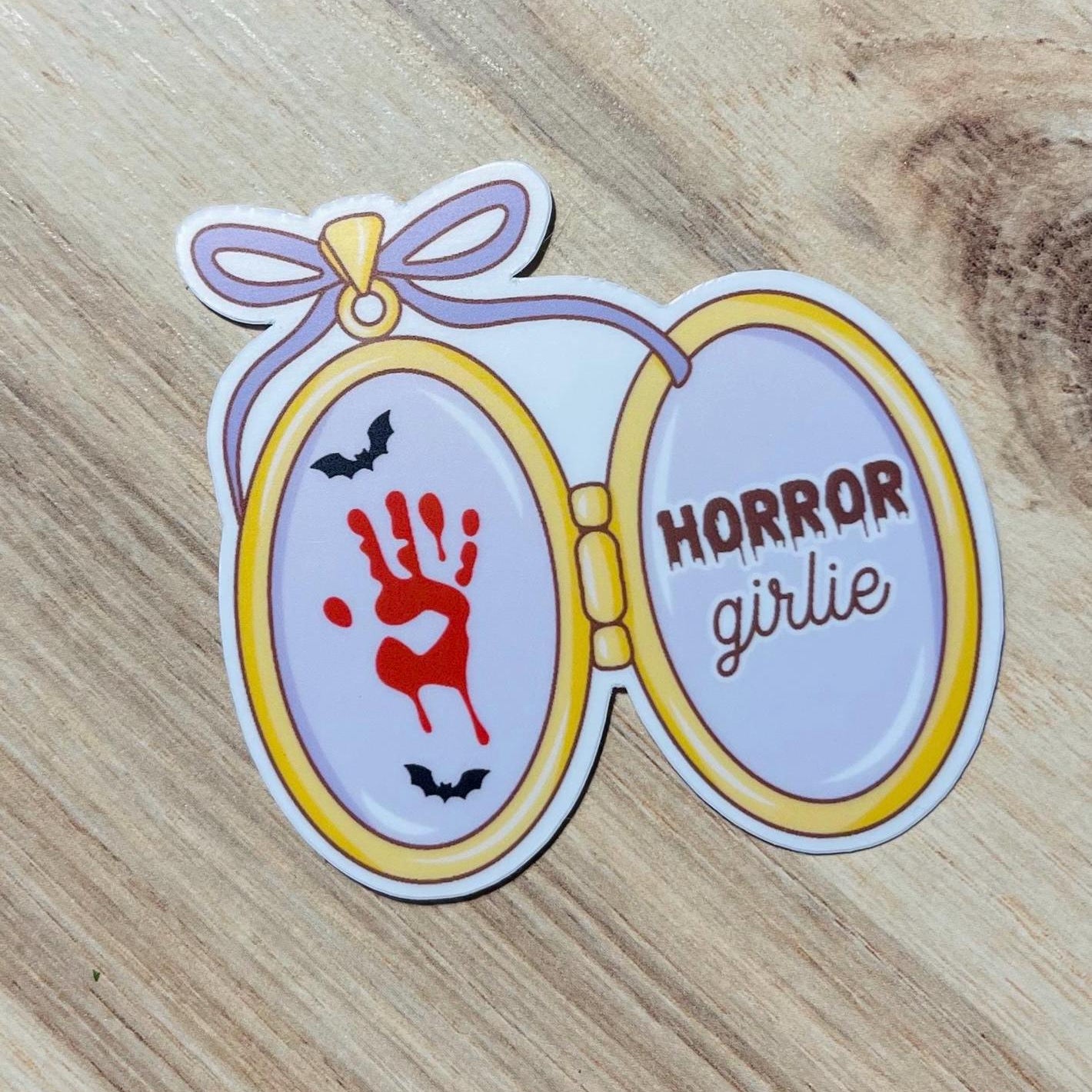 Sticker with 'Horror girlie' design on a wooden surface