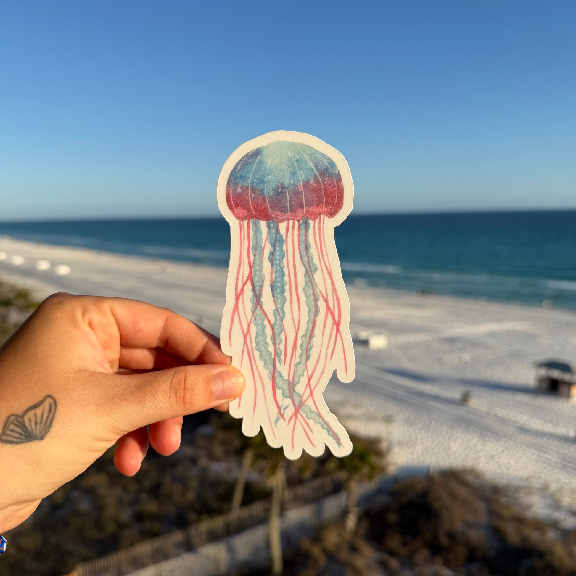 hand holding a jellyfish shaped bookmark against  beach background