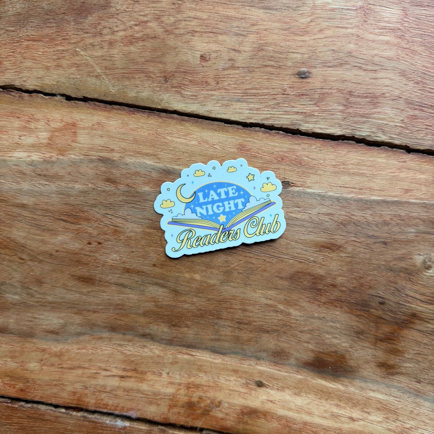 Sticker with 'Late Night Readers Club' text on a wooden surface