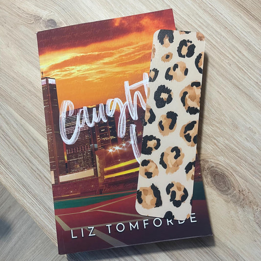 leopard print bookmark on top pf a book on a wooden surface