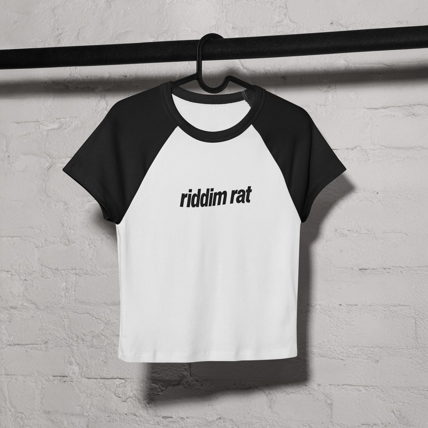 Black and white baseball shirt with a design on a hanger against a textured wall.
