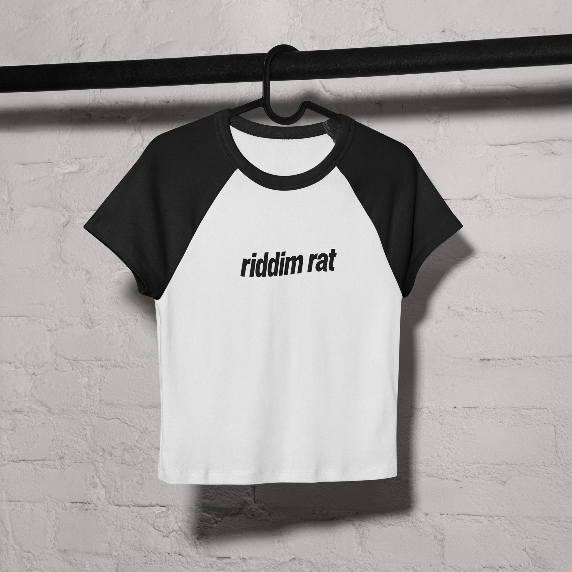 Black and white baseball shirt with a design on a hanger against a textured wall.