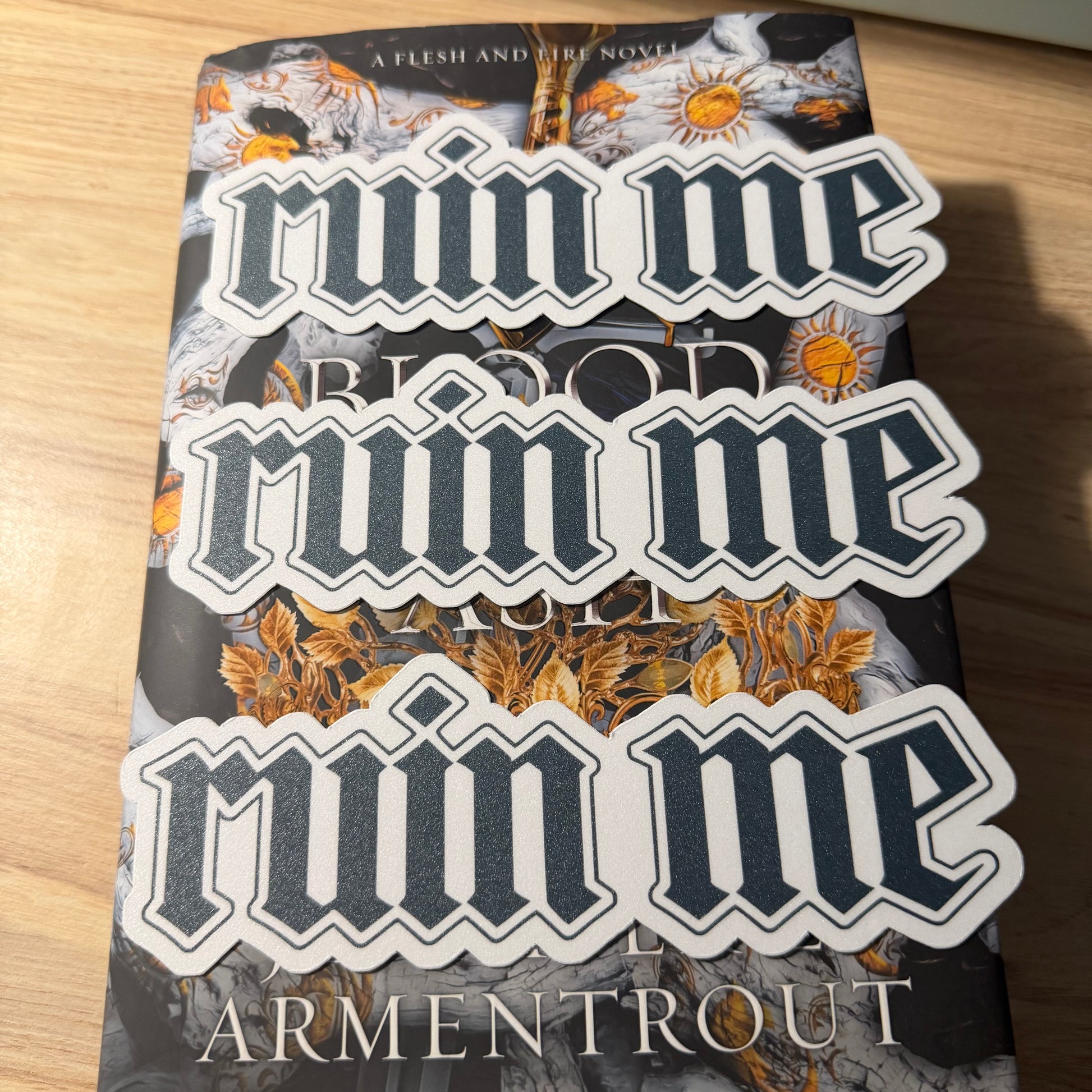 a book with ruin me bookmarks laying on top of it on a wooden surface