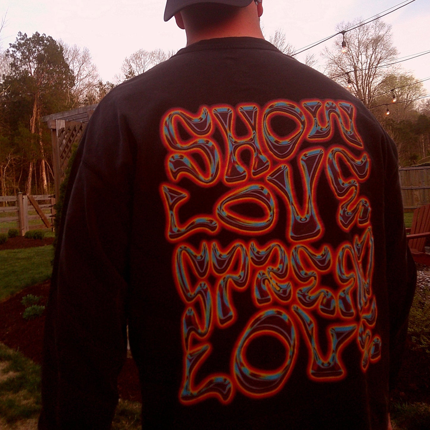 Person wearing a black long sleeve with colorful text on the back, standing outdoors.
