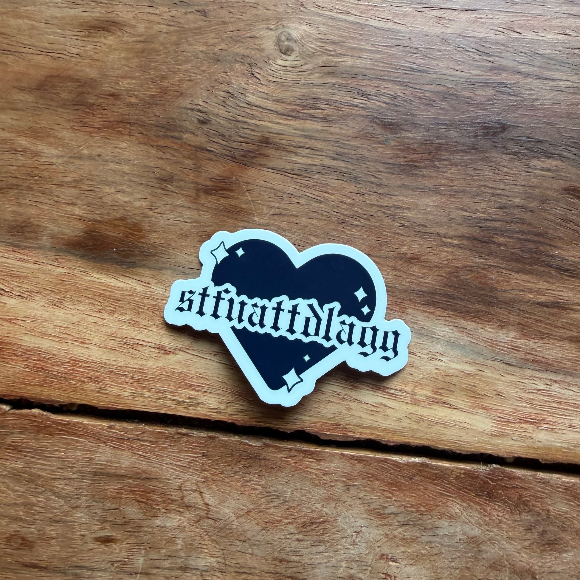 Heart-shaped sticker with text on a wooden surface