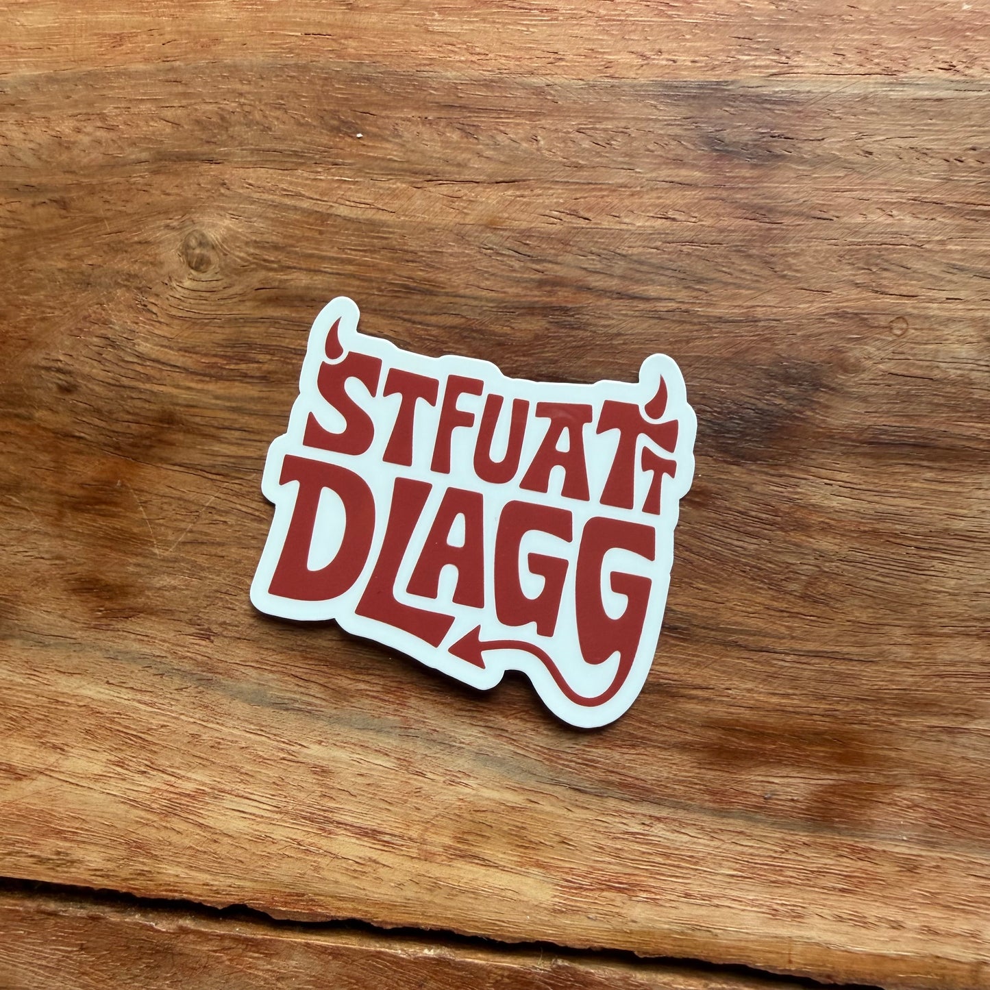 Sticker with 'STUART DLAGG' text on a wooden surface