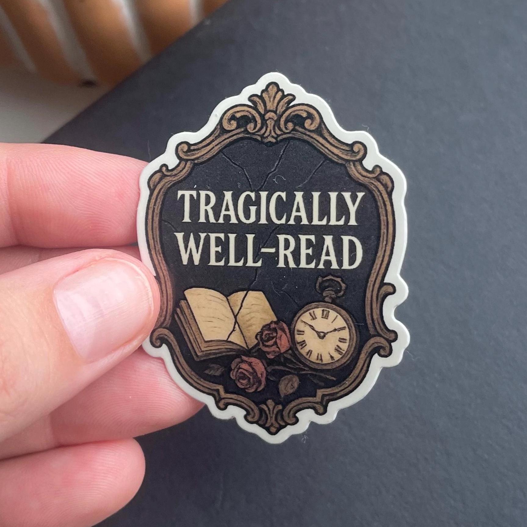 Sticker with 'Tragically Well-Read' design held by a hand against a dark background
