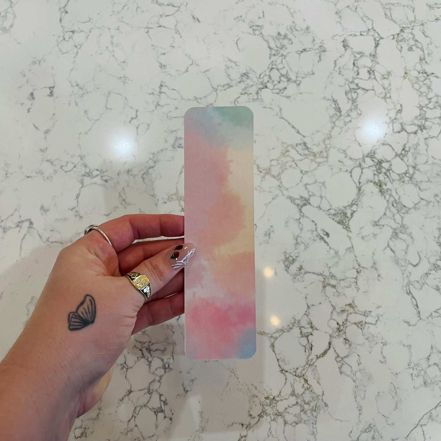 Hand holding a colorful bookmark on a marble surface