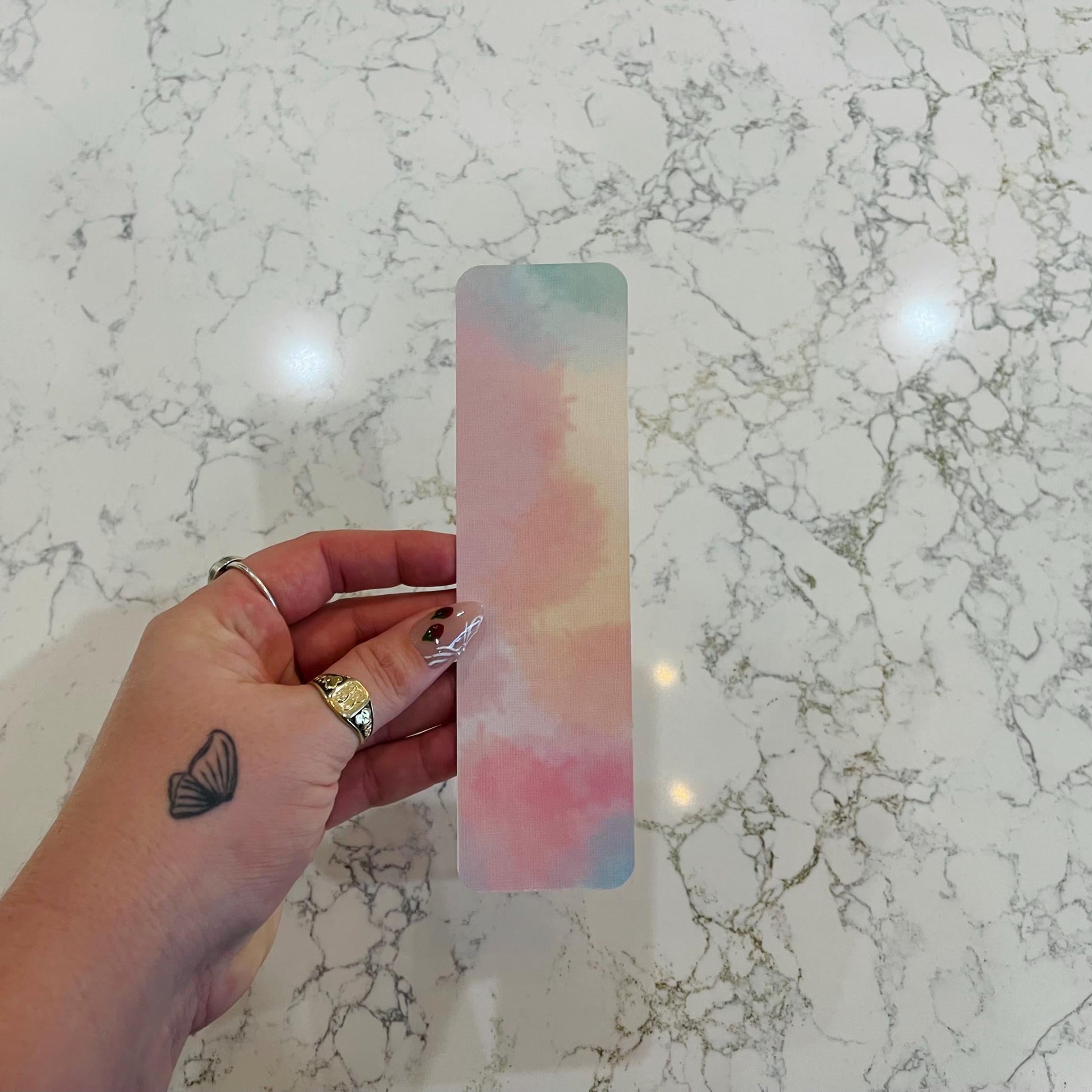 Hand holding a colorful bookmark on a marble surface