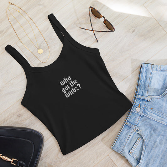 black tank top with text, sunglasses, necklace, and jeans on a light wooden surface