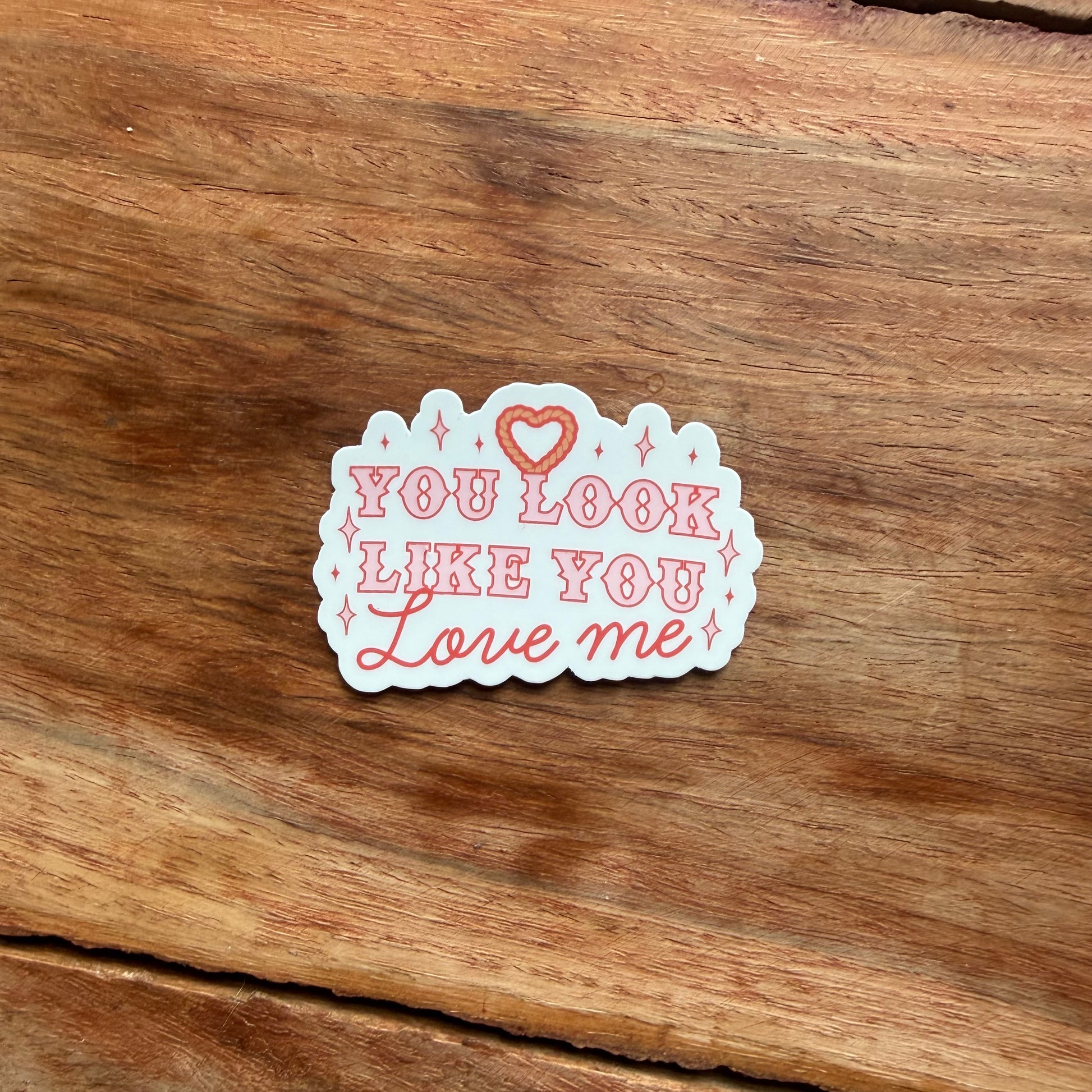Sticker with 'You Look Like You Love Me' text on a wooden surface